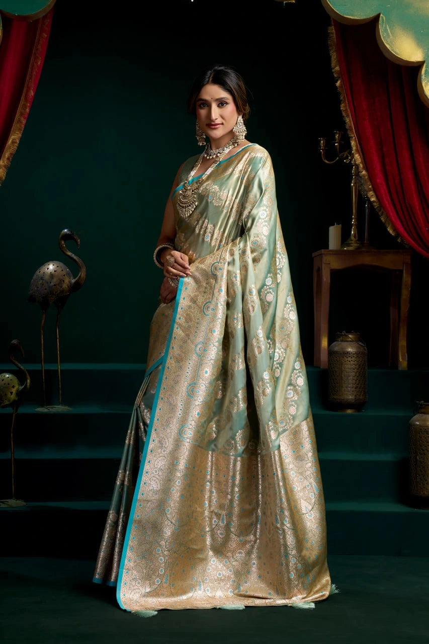 Woman in a traditional saree standing in a decorative setting with red curtains and green steps.